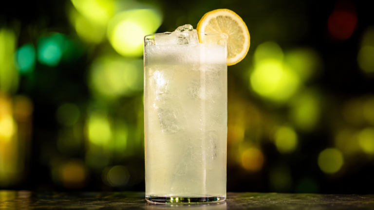 Gin Fizz vor extrem unscharfem Neonhintergrund in der Farbe des Drinks