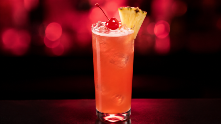 Singapore Sling vor extrem unscharfem Neonhintergrund in der Farbe des Drinks