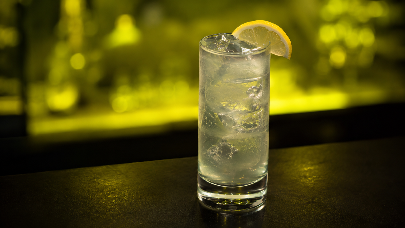 Vodka Lemon vor extrem unscharfem Neonhintergrund in der Farbe des Drinks